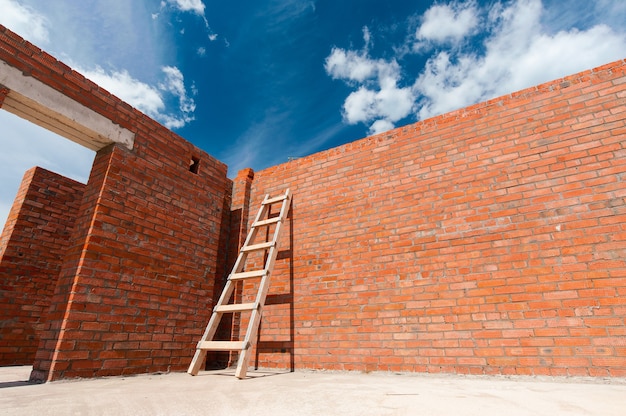 Ziegelrote Wand eines neuen Hauses auf einem Hintergrund des blauen Himmels