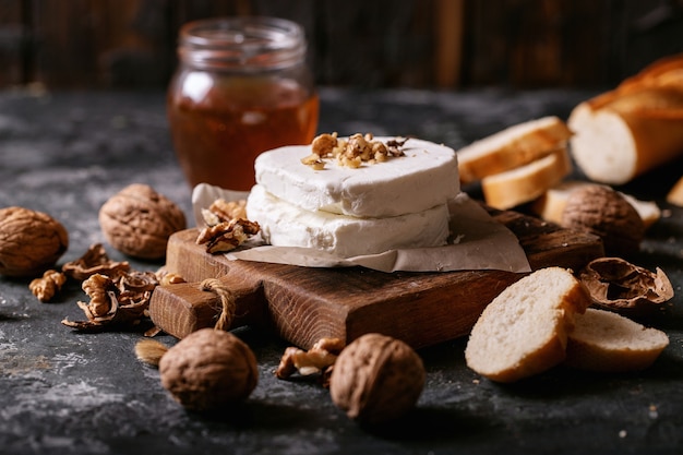 Ziegenkäse serviert mit Honig und Walnüssen über dunklem Texturhintergrund. Speicherplatz kopieren