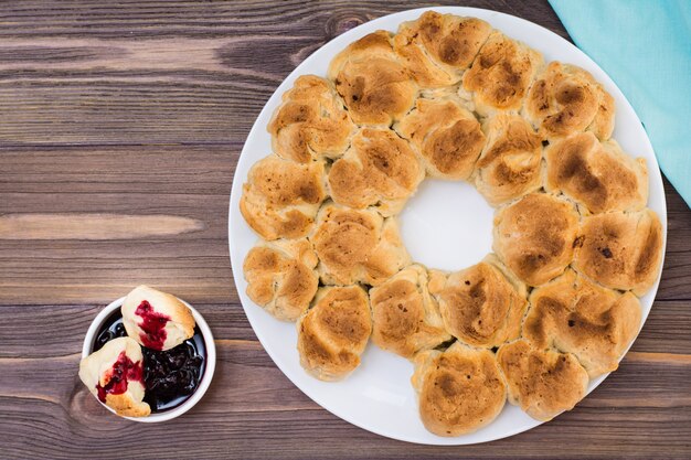 Ziehen Sie Affenbrot mit Marmelade der Schwarzen Johannisbeere in einer Platte auf einer hölzernen Platte auseinander. Ansicht von oben