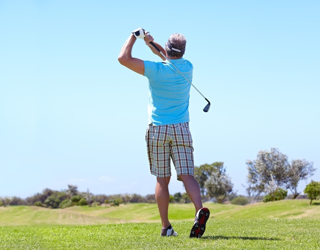 Zielen auf das Grün Rückansicht eines reifen männlichen Golfspielers, der einen Schlag spielt