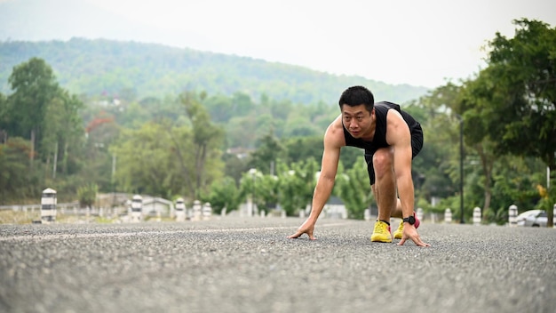 Zielstrebiger und fitter reifer asiatischer Mann ist mit einer Ausgangsposition unterwegs