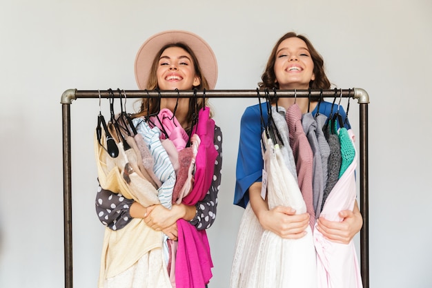 Ziemlich aufgeregte junge Frauen Shopaholics wählen Kleidung.