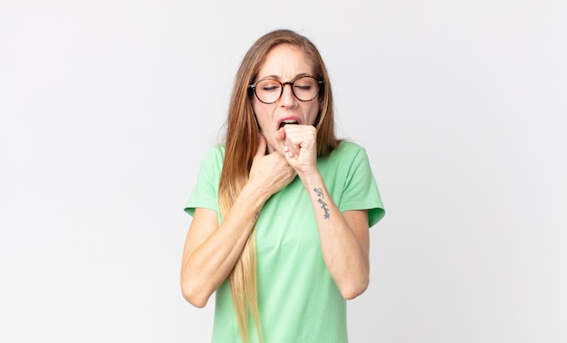 Ziemlich dünne Frau, die sich mit Halsschmerzen und Grippesymptomen krank fühlt und mit bedecktem Mund hustet