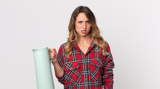 Foto ziemlich dünne frau, die sich verwirrt und verwirrt fühlt und eine kaffee-thermoskanne hält