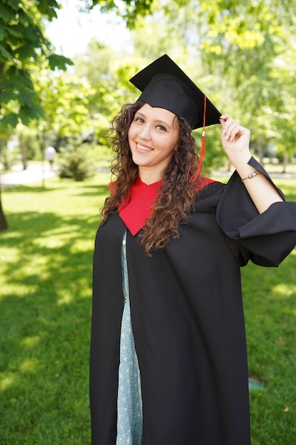 Ziemlich frischer Absolvent im Freien in der Nähe der Universität