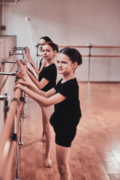 Ziemlich glückliche mädchen machen beim täglichen ballettunterricht kraftübungen.