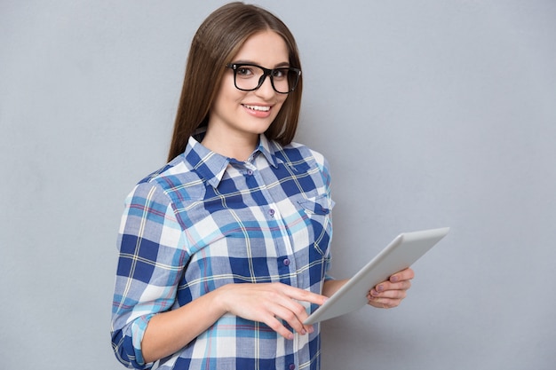 Ziemlich glücklicher Student in Brille und kariertem Hemd mit Tablet und Lächeln