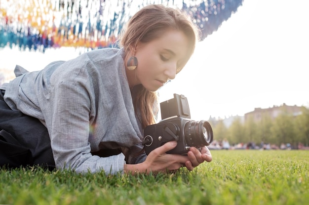 Ziemlich kaukasische Frau mit Filmfotokamera Reisende Frau, die im Sommer ein Foto mit einer Vintage-Kamera im Freien macht