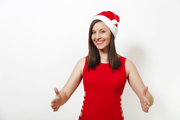 Ziemlich kaukasische glückliche Frau mit rotem Kleid und Weihnachtsmütze, die Kopienraum zwischen Palmen für Werbung oder Text auf weißem Hintergrund hält. Sankt-Mädchen isoliert. Neujahrsfeiertag 2018 Konzept.