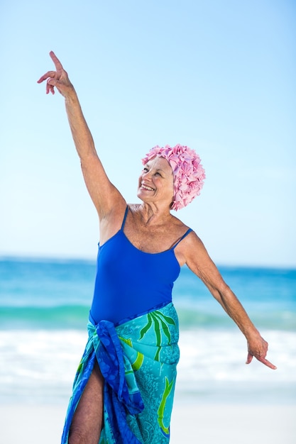 Ziemlich reife Frau, die ihre Arme am Strand hebt