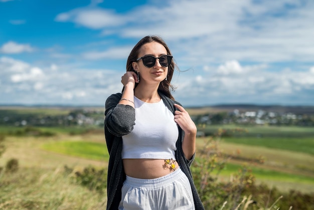 Ziemlich schlanke junge Frau, die im Sommer auf dem grünen Feld spazieren geht