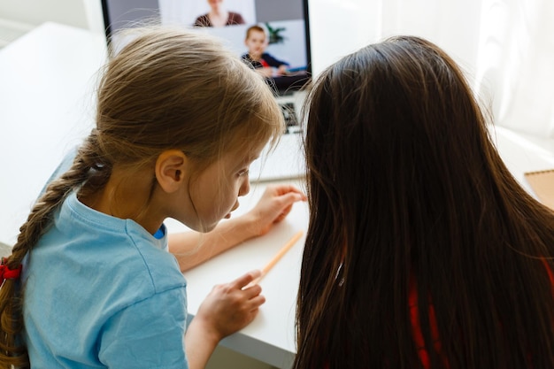Ziemlich stilvolle Schulmädchen, die während ihres Online-Unterrichts zu Hause lernen, soziale Distanz während der Quarantäne, Selbstisolation, Online-Bildungskonzept