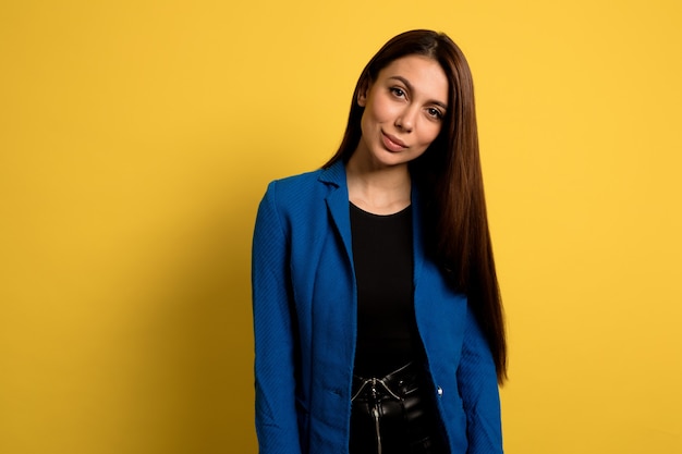 Ziemlich stilvolles Mädchen mit nacktem Make-up und langen dunklen Haaren während des Fotoshootings über der isolierten Wand