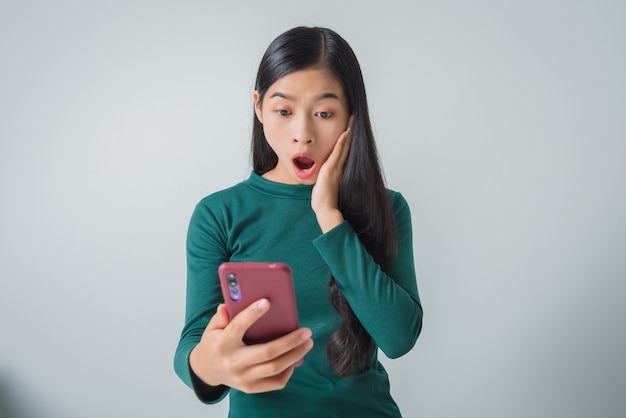 Ziemlich überraschte junge Frau hält Smartphone