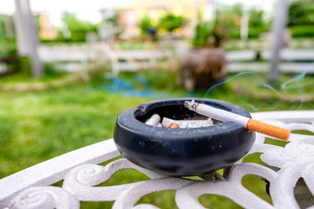 Zigarette brennt mit Rauch auf Keramik Aschenbecher