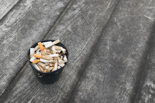 Zigarette im Freienaschenbecher mit Sand auf Bretterboden