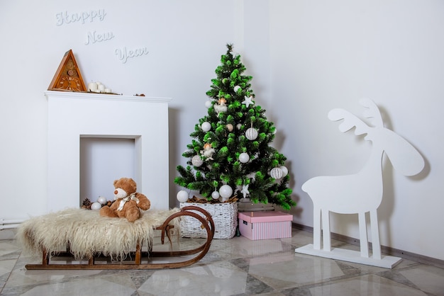 Zimmer mit Weihnachtsdekoration dekoriert. Weihnachtsbaum, Kamin, Schlitten und Rentier.