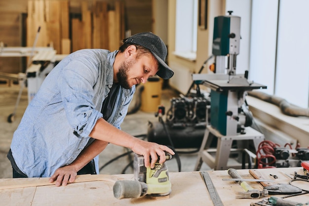 Foto zimmermann arbeitet mit holz in der schreinerei. mann erledigt holzarbeiten professionell