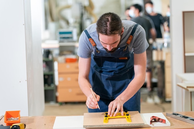 Zimmermann, der am Holzarbeitstisch und an Möbeln arbeitet, die mit Holz handgefertigt sind