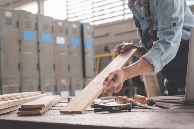 Zimmermann, der mit Ausrüstung auf Holztisch in der Tischlerei arbeitet Frau arbeitet in einer Tischlerei
