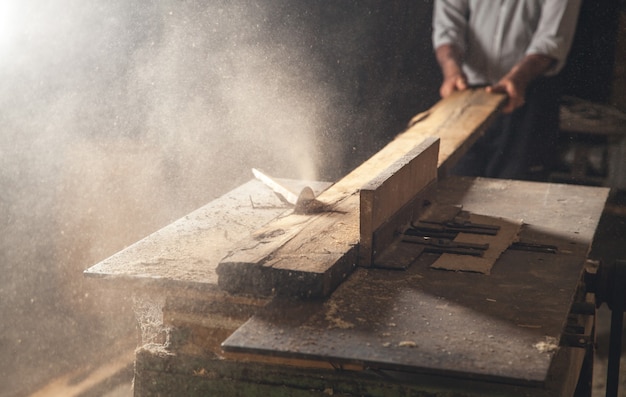 Zimmermann schneidet ein Holzbrett mit einer Tischlermaschine.