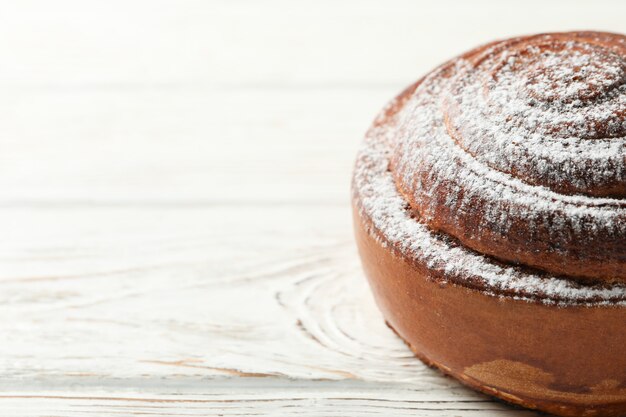 Zimtschnecke mit Puderzucker auf weißem Tisch