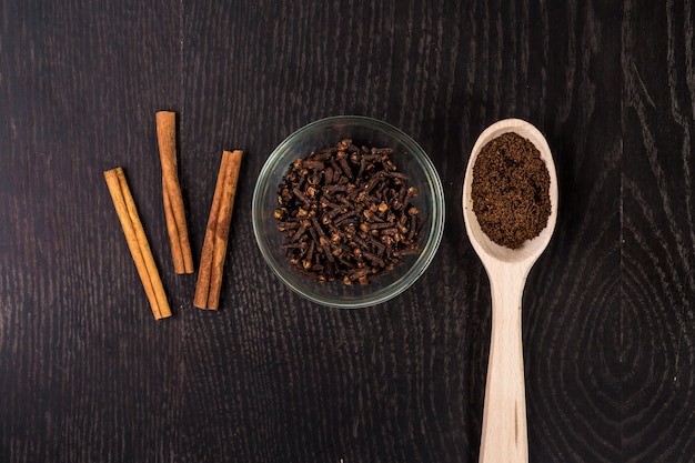 Zimtstangen, Kaffee, Nelken auf schwarzem Hintergrund