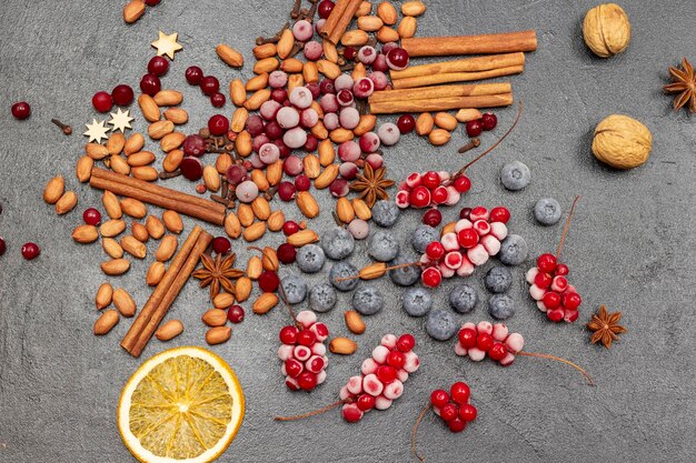 Zimtstangen Nüsse gefrorene Beeren und Orangenchips Schwarzer Hintergrund