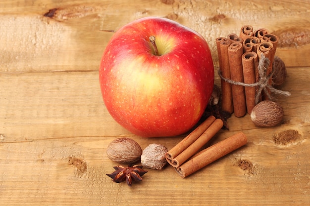 Zimtstangen, roter Apfel, Muskatnuss und Anis auf Holztisch
