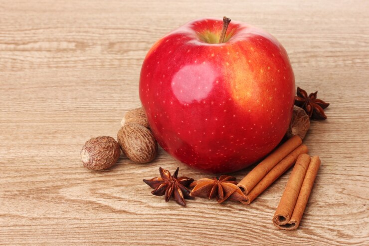 Foto zimtstangen, roter apfel, muskatnuss und anis auf holztisch