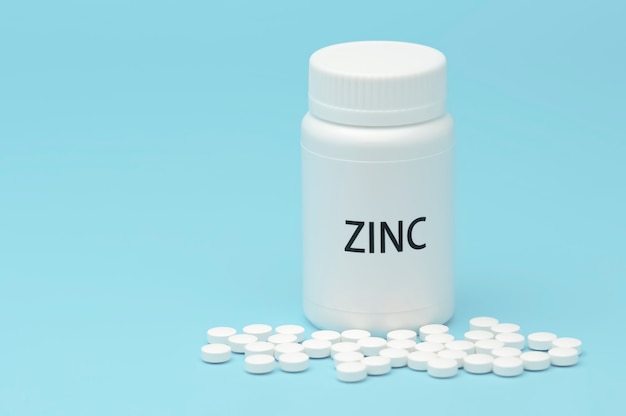 ZINC en envase de botella blanca con pastillas dispersas.