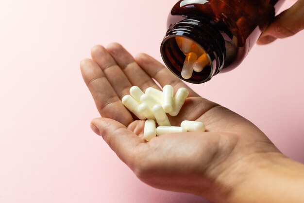 Zinktabletten in der Hand auf rosafarbenem Hintergrund