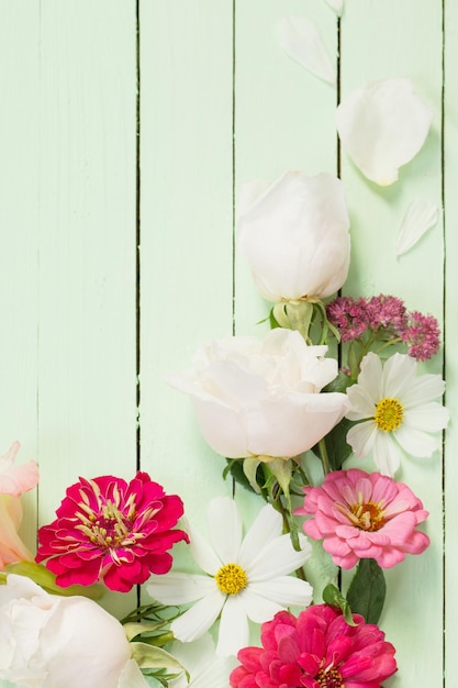 Zinnienblüten auf grünem Holzhintergrund