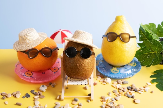 Foto zitrone, kiwi und mandarine in hüten und sonnenbrillen am strand