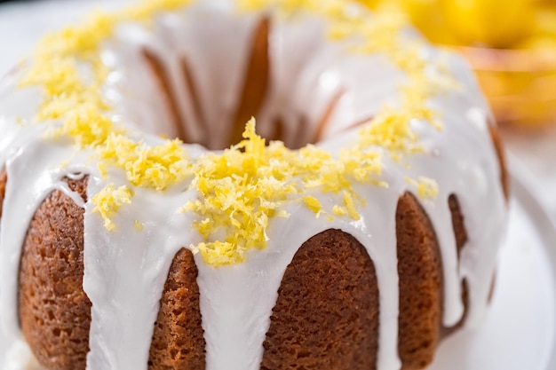 Zitronen-Bundt-Kuchen dekoriert mit Zitronenschale auf einem Tortenständer.