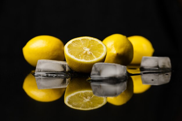 Zitronen und Eis auf schwarz reflektierter Oberfläche