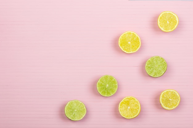 Zitronen- und Limettenhälften auf rosa Holzhintergrund