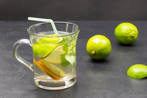 Zitronengetränk mit grünem Basilikum in einem Glas Limetten auf dem Tisch