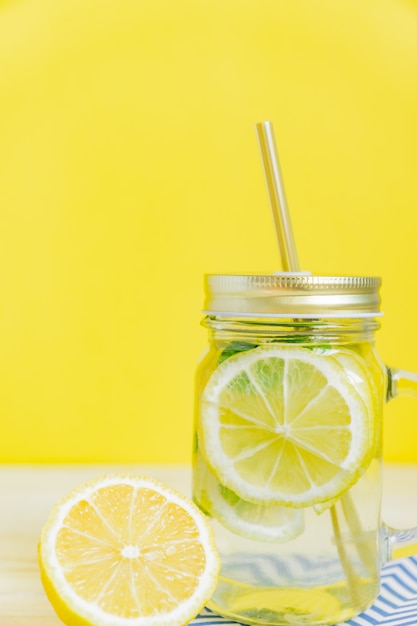 Zitronenlimonadenwasser mit geschnittenem Zitronen- und Minzen-, gesundem und Detoxwassergetränk im Sommer auf gelbem Hintergrund. Heller Hintergrund des Sommers mit Kopienraum