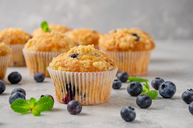 Zitronenmuffins mit Blaubeeren und Shtreisel mit frischen Beeren auf einem grauen Betonhintergrund.