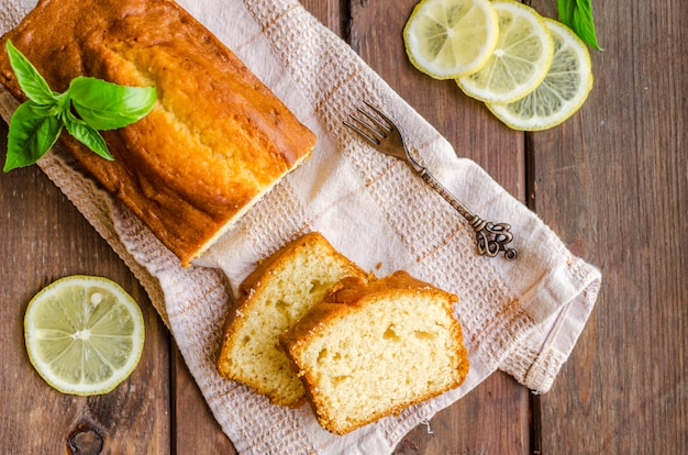 Zitronenpfundkuchen auf rustikalem hölzernem Hintergrund mit Zitrone.