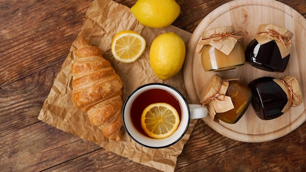 Zitronentee hausgemachte Marmeladengläser Marmelade oder Quarkcroissant auf Holztisch Frühstückskonzept Fröhlicher Morgen