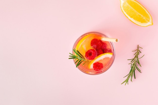 Zitronenwasser oder Limonade mit Himbeere und Rosmarin auf rosa Hintergrund, Draufsicht. Aromatischer cooler Cocktail für die Sommerhitze.