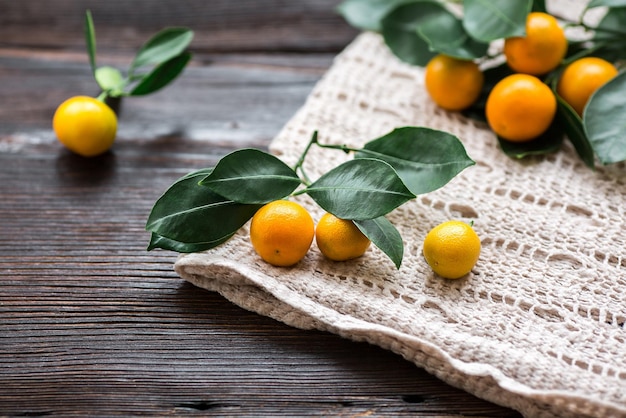 Zitrus Calamondin mit Blättern auf Leinenserviette auf Holzbrett