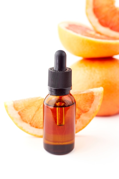 Zitrus- oder Grapefruitöl in Glasflasche mit frischer Grapefruit auf weißem Hintergrund. Spa- und Hautpflegeprodukt