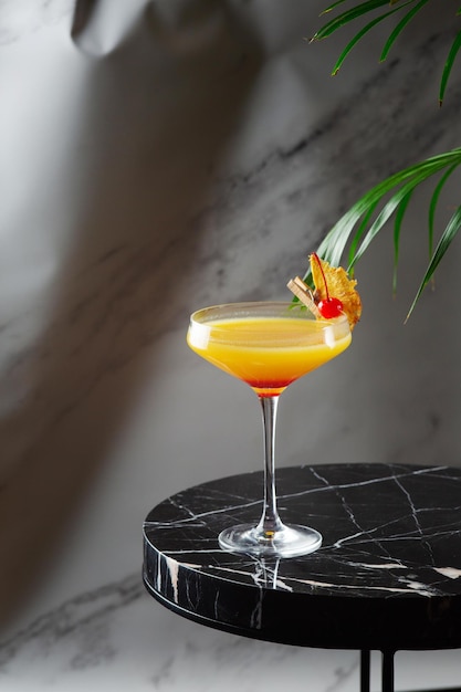 Zitrus- und Ananascocktail auf Marmortisch hautnah. tropischer Cocktail auf Schattenhintergrund