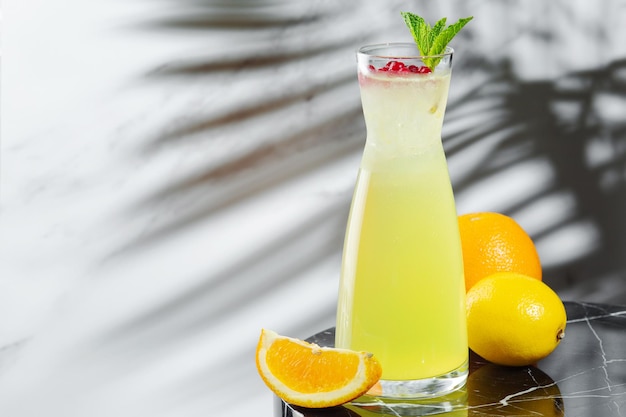 Zitrus- und Preiselbeerlimonade mit Zutaten auf dem Tisch. Hausgemachte Limonade mit Eis. kalte Limonade mit frischen Himbeeren, Minze und Zitrus im Krug