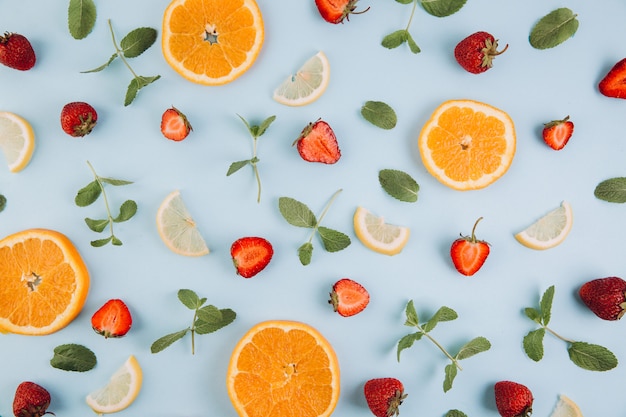 Zitrusfrüchte, Blätter und Erdbeeren auf dem blauen Holztisch.