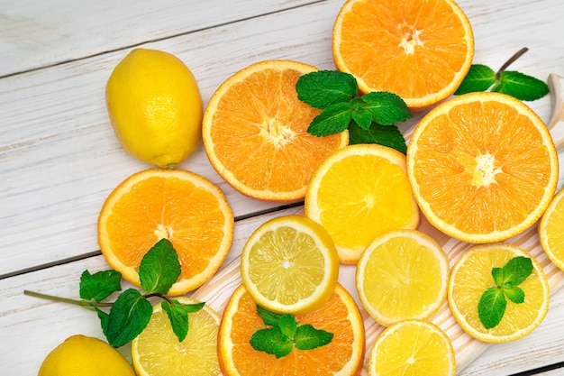 Zitrusfrüchte. Orangen, Zitronen und Minze. Geschnittene Zitrusfrüchte auf einem hölzernen Hintergrund.