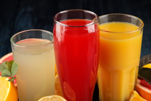 Zitrussäfte. Orangen-, Grapefruit- und Zitronensaft mit frischen Früchten auf einem blauen Holztisch.